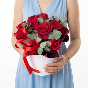 Красные розы в шляпной коробке и зелень